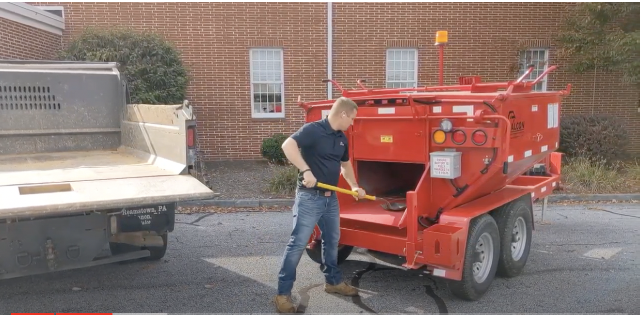 A worker demonstrates how easy it is to shovel asphalt from a hot box.