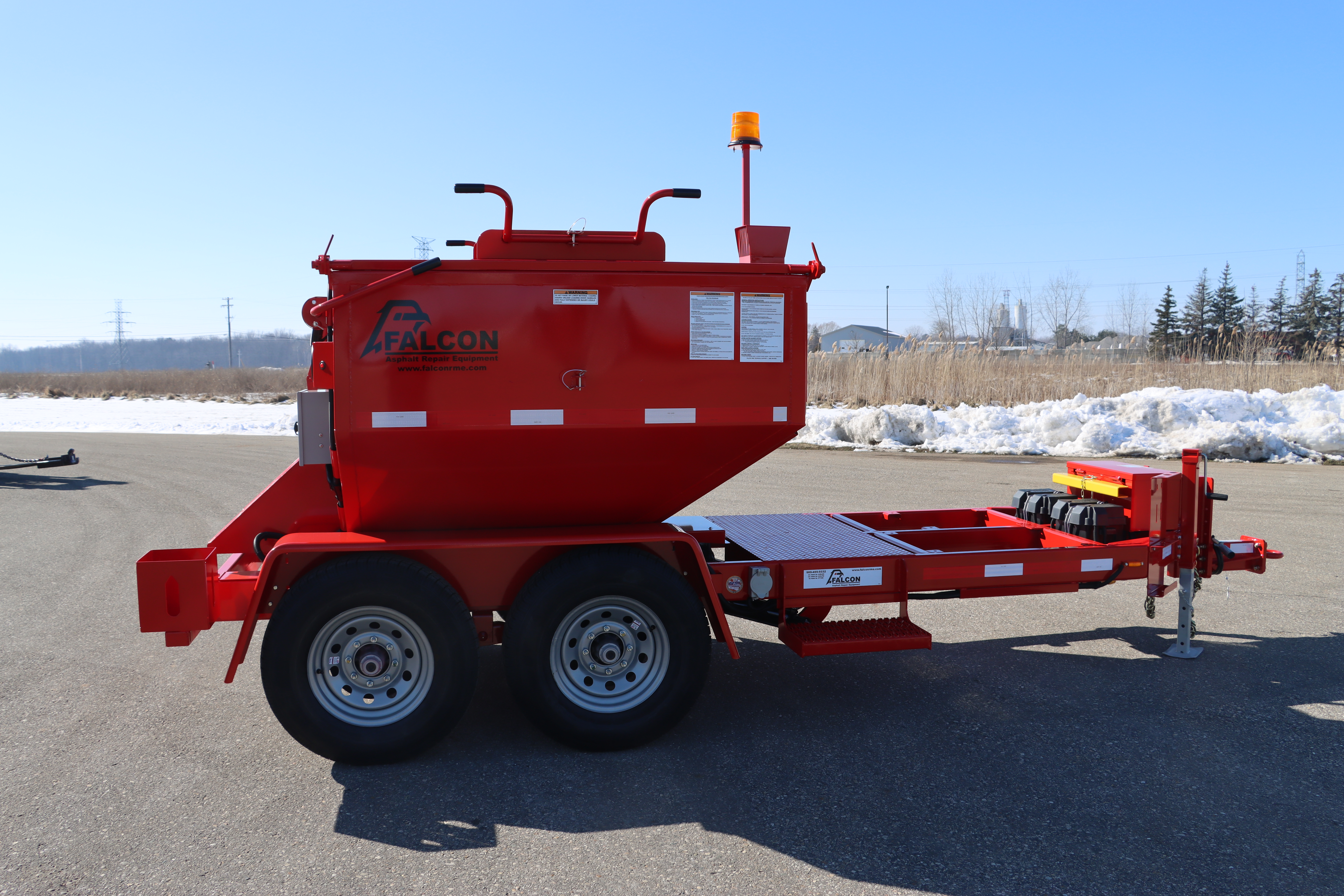 The front view of a red 6-ton Falcon asphalt hot box.